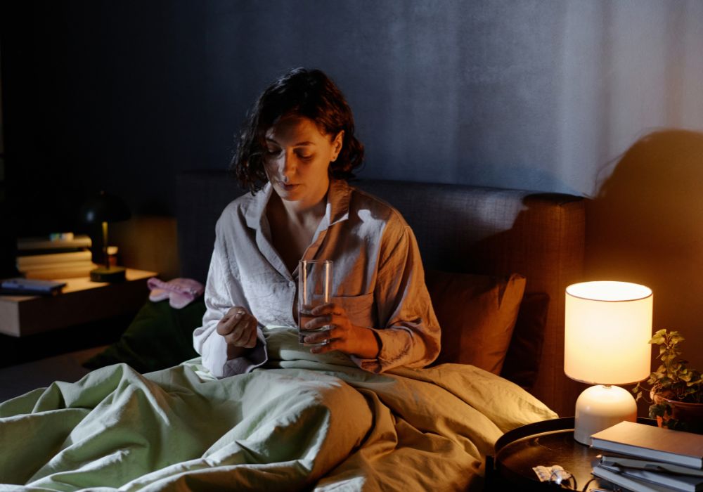 Mujer en pijama, sentada en la cama con luz tenue y ambiente calmado, padeciendo insomnio en la menopausia y dificultad para dormir por la noche