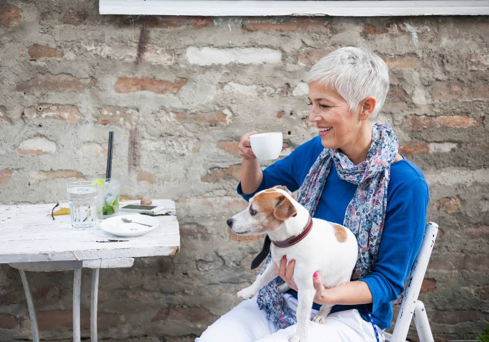 Mujer pasando un buen rato con su perro en un entorno tranquilo, como señal de bienestar emocional con mascotas en la menopausia