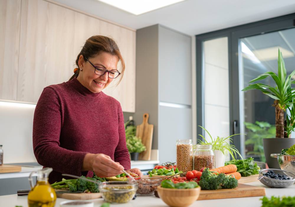Mujer en menopausia preparando alimentos saludables en su cocina, cuidando su alimentación en la menopausia
