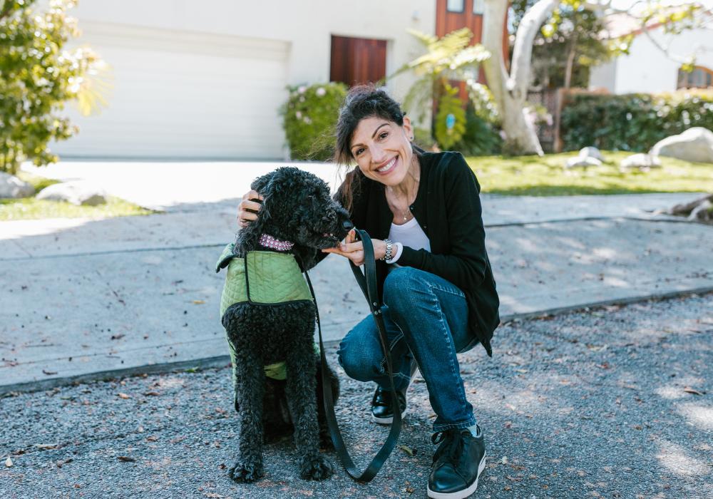 Mujer agachada sonriendo junto a su mascota, mostrando que el paseo diario con tu perro activa la oxitocina y reduce el cortisol