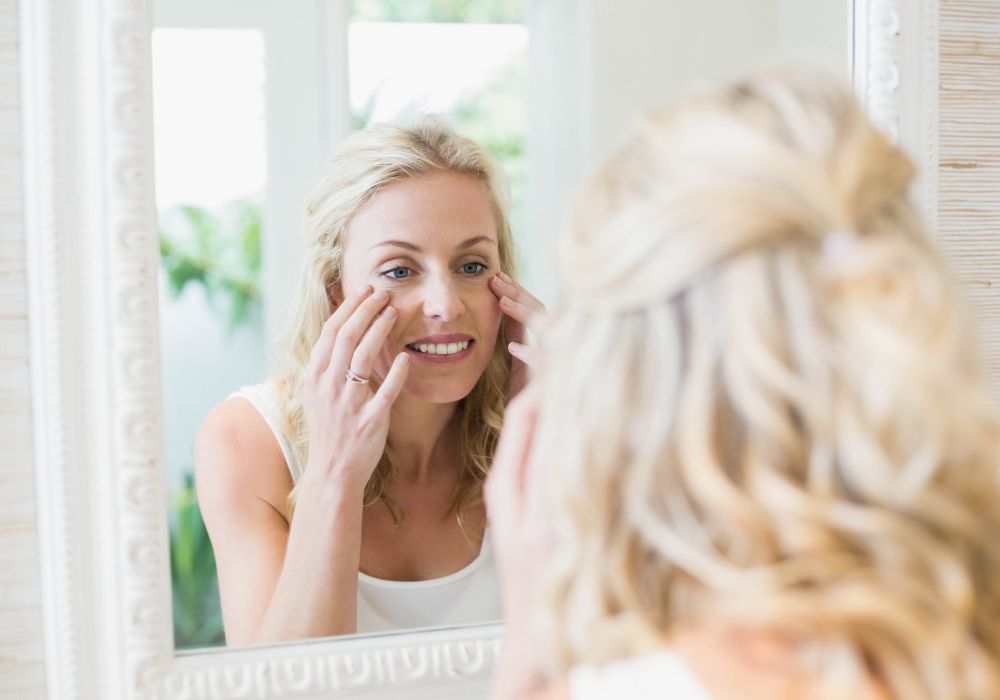 Woman standing in front of a mirror, noticing the changes in her skin during perimenopause