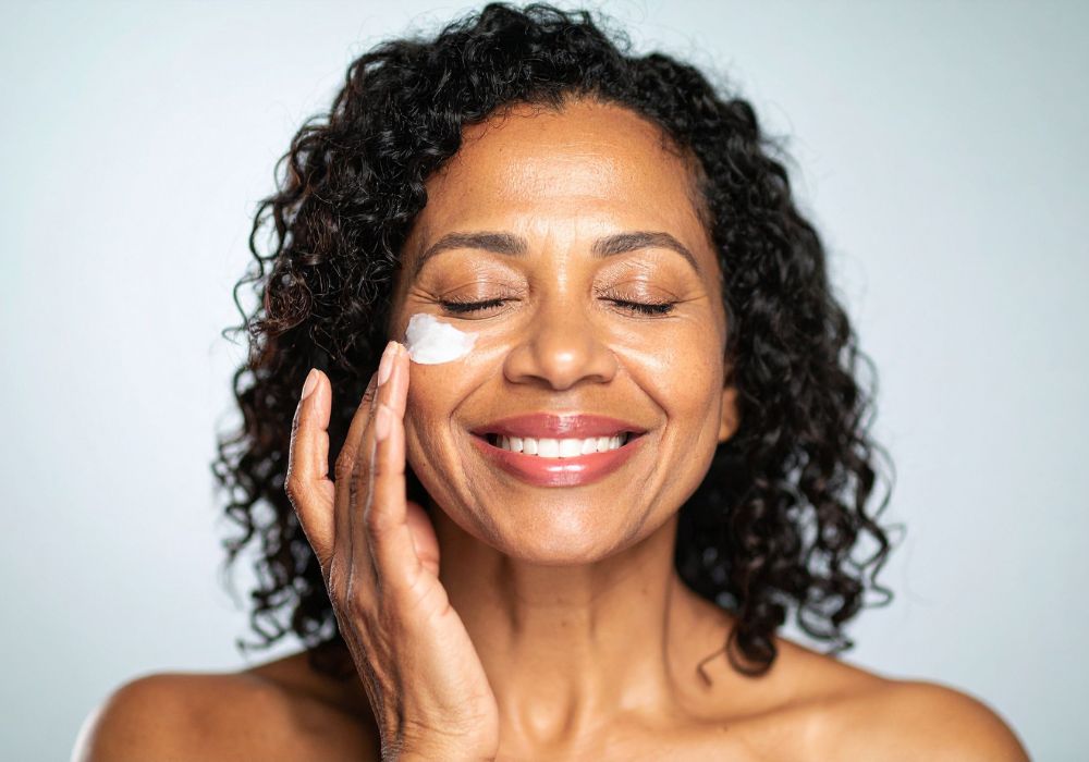 Woman moisturizing her skin during perimenopause as part of her daily self-care routine