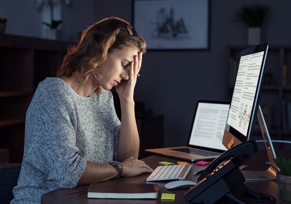 Mujer sintiendo los efectos del cortisol en la menopausia frente a su computadora